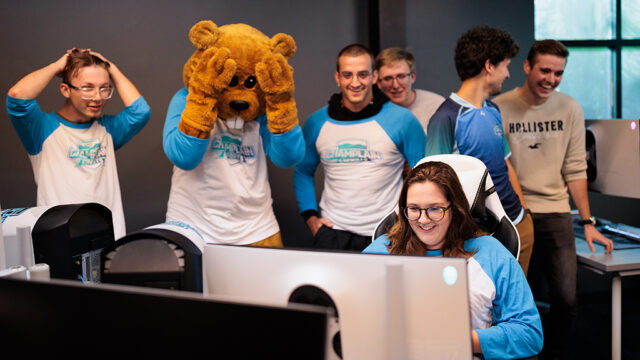 Students and Chauncey the mascot watching a student play a computer game
